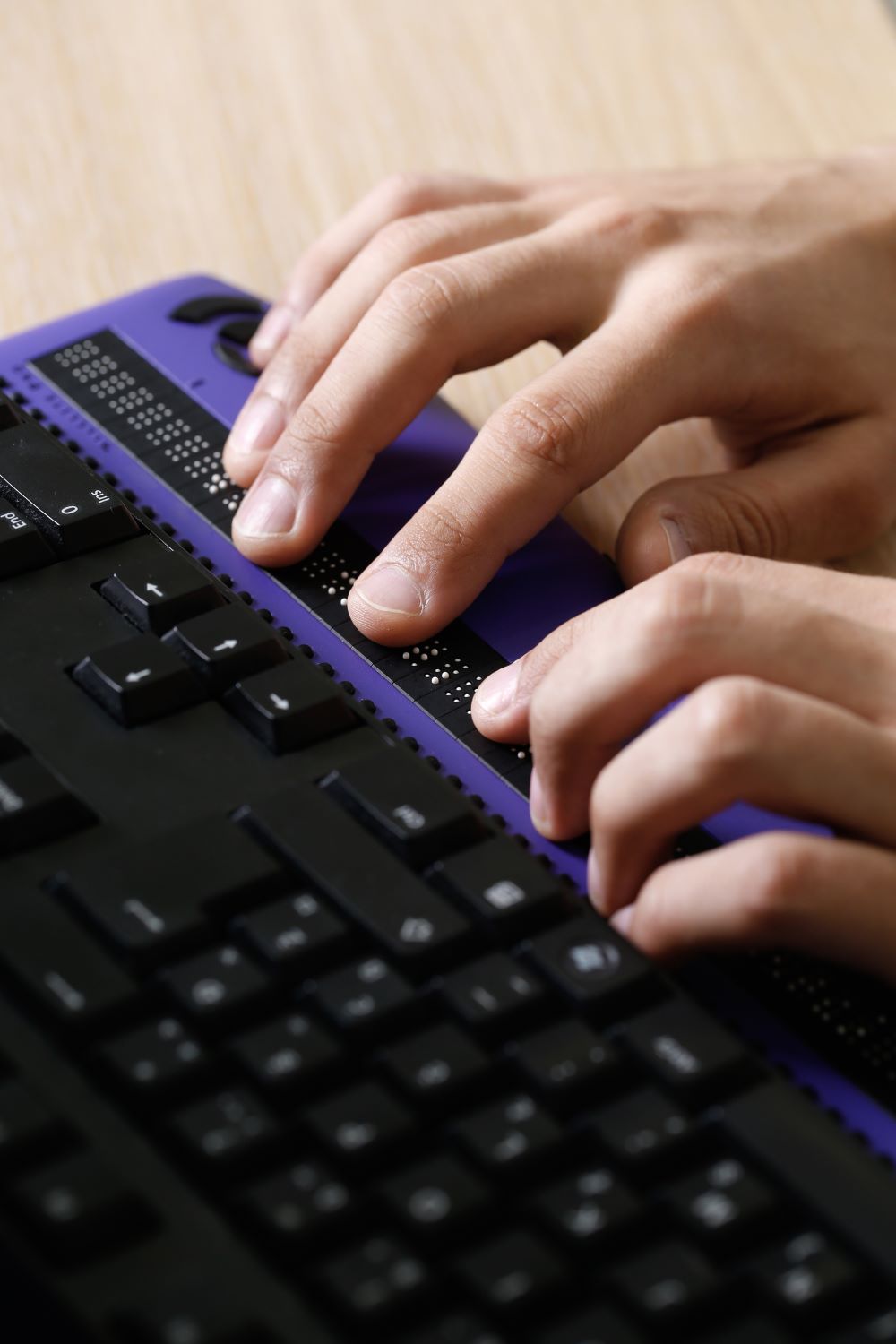 Blind person using computer with braille computer display and a computer keyboard