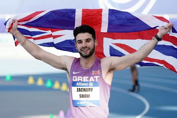 Picture of Zac Shaw, Accessibility Lead at CACI Digital Experience, holding aloft a Union Jack flag after winning a medal at the 2023 World Para Athletics Championships in the 100m sprint