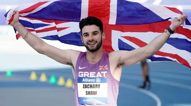 Picture of Zac Shaw, Accessibility Lead at CACI Digital Experience, holding aloft a Union Jack flag after winning a medal at the 2023 World Para Athletics Championships in the 100m sprint