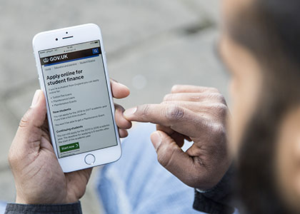 Photo taken over the shoulder of a user holding an iPhone with the GOV.UK website loaded