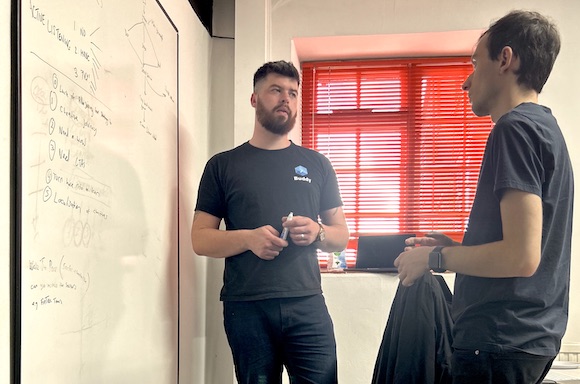 Photo of Sam and Nacho in the Cyber-Duck office discussing DevOps at a whiteboard